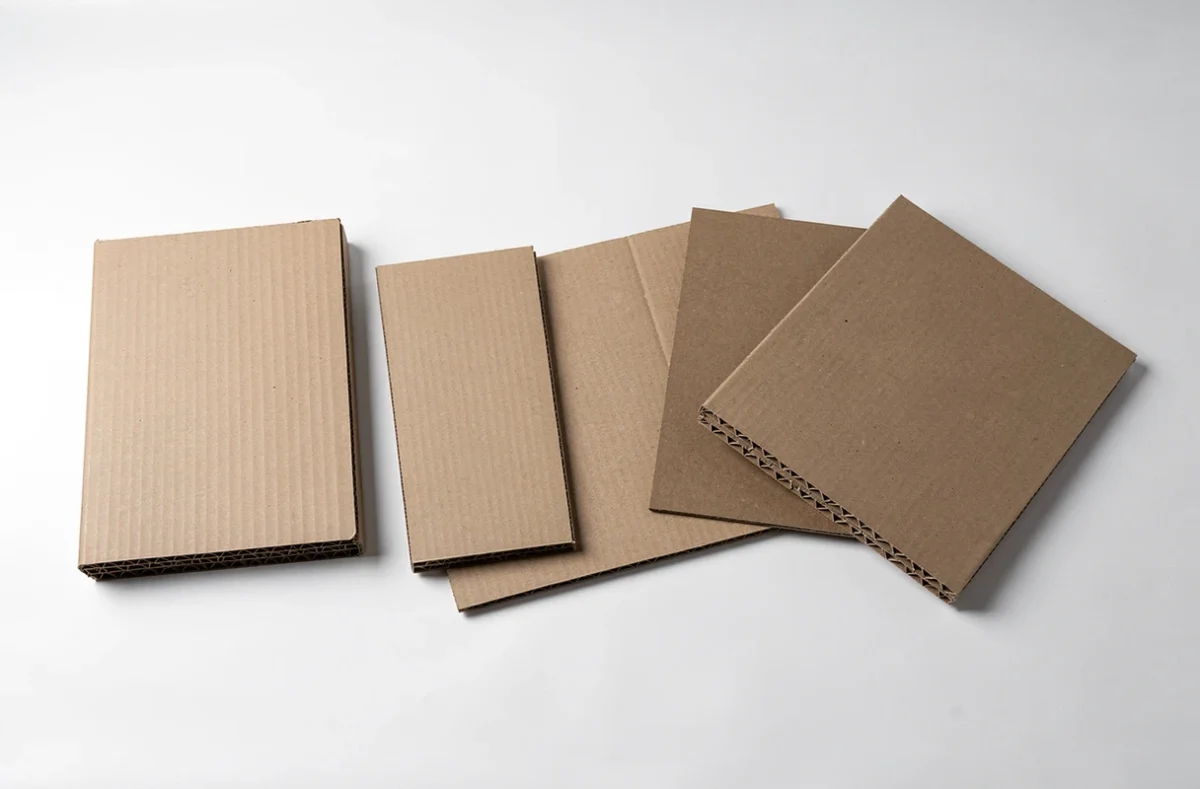 Comparatif de différents types de cartons : ondulé, simple épaisseur et kraft disposés côte à côte